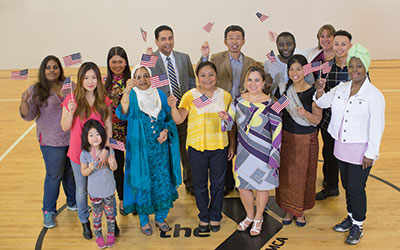 A group of new Americans each holding a U.S. Flag